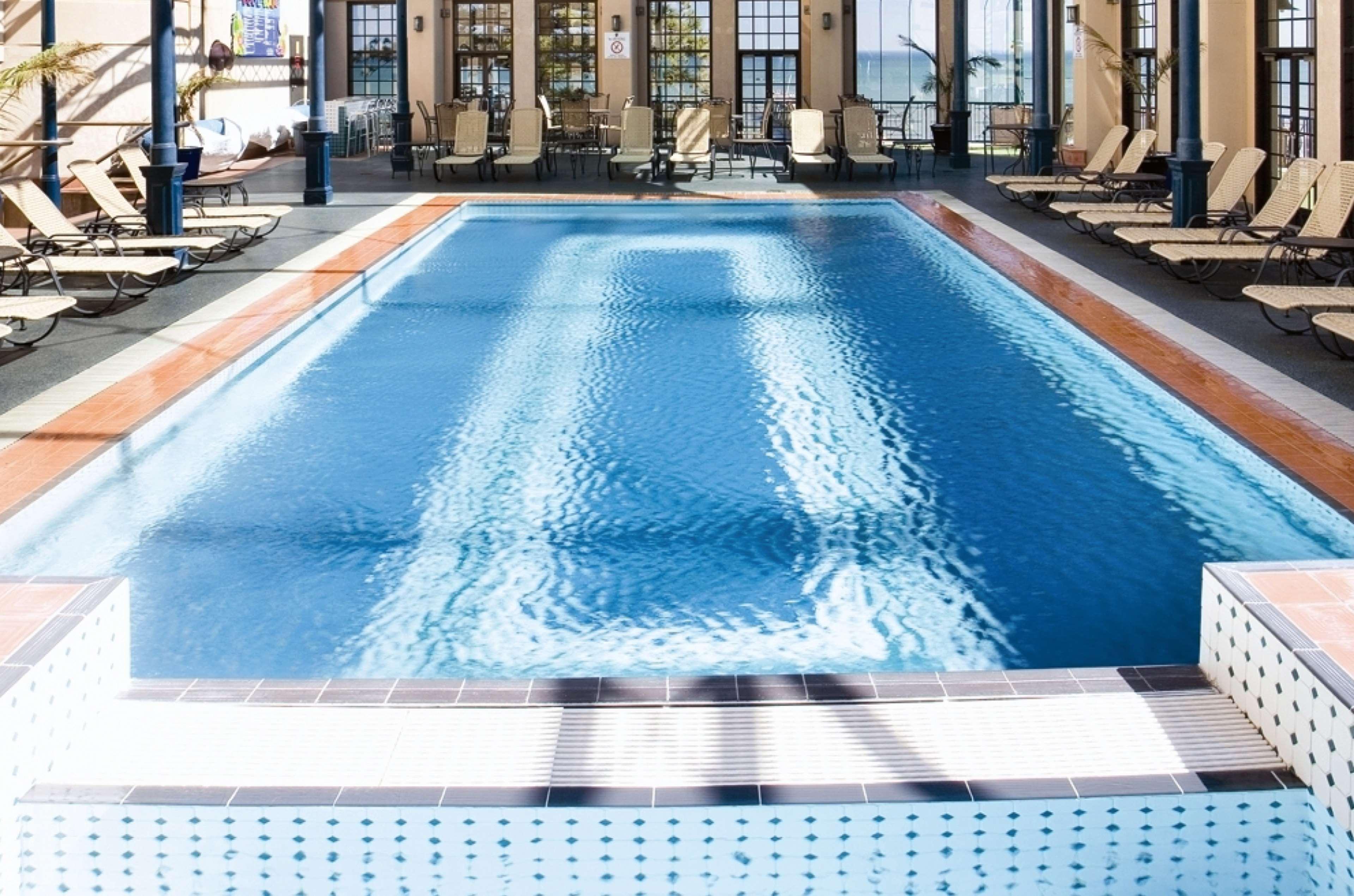 Отель Stamford Grand Adelaide Гленелг Экстерьер фото The photo shows an indoor swimming pool with a pristine blue surface. The pool is surrounded by a tiled deck and has lounge chairs lined up along the sides. Large windows allow natural light to flood the area, creating a bright and inviting atmospher