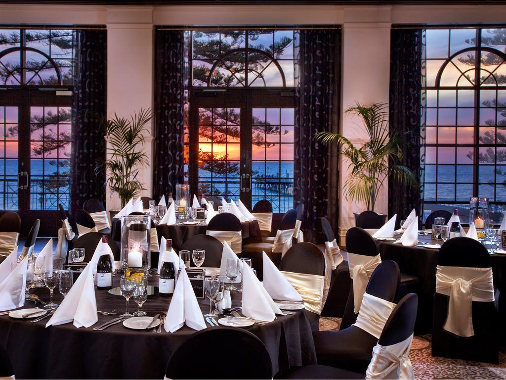 Отель Stamford Grand Adelaide Гленелг Экстерьер фото The photo shows an elegant dining setup inside a venue with large windows. The tables are adorned with black tablecloths and white napkins arranged in a stylish manner. Each table has glassware and other dining utensils placed neatly. In the backgrou